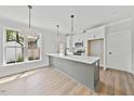 Modern kitchen featuring a gray island, white cabinets, stainless steel appliances, and pendant lighting at 313 W Murray Ave, Durham, NC 27704