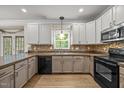 Well-lit kitchen with white cabinets, tile backsplash, and modern appliances at 3306 Meadowrun Dr, Durham, NC 27707