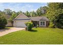Charming single-story home featuring a well-maintained lawn and two-car garage at 413 Braxman Ln, Holly Springs, NC 27540