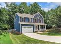 Charming two-story home with a blue exterior, red door, white trim, a long driveway, and a green lawn at 605 Catlin Rd, Cary, NC 27519