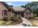 Charming brick home featuring manicured landscaping, red shutters, and a covered front porch at 9 Piney Grove Rd, Bahama, NC 27503