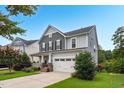 Charming two-story home with a well-maintained lawn, inviting front porch with stone details, and a convenient two-car garage at 908 Woodland Grove Way, Wake Forest, NC 27587