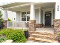 Inviting front porch with stone pillars, a seating area, decorative plants and a welcoming entrance with stylish door at 908 Woodland Grove Way, Wake Forest, NC 27587