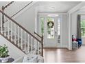 Bright foyer features wood floors, a staircase, and a glass front door with a wreath at 909 Green Oaks Pkwy, Holly Springs, NC 27540