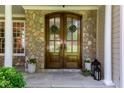 Elegant stone exterior with a beautiful double front door, complemented by stylish potted plants at 102 Bosswood Ct, Cary, NC 27518