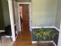 Hallway featuring hardwood floors, decorative plant, and an open doorway leading to another room at 104 Belle Isle Ct, Cary, NC 27513