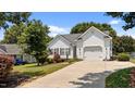 View of a house featuring a wide driveway, a two-car garage, and lush greenery at 113 Kelly Ln, Clayton, NC 27520