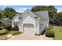 View of a two-car garage attached to a white house, surrounded by landscaping and a well-manicured lawn at 113 Kelly Ln, Clayton, NC 27520