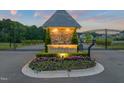 Grand Highland Estates illuminated entrance featuring stone accents, decorative flowers, and gated access at 1725 Legacy Ridge Ln, Wake Forest, NC 27587