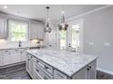 Stylish kitchen featuring a granite island, white cabinets, modern appliances, and contemporary lighting at 189 Churchill Way, Clayton, NC 27520