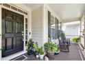 Inviting front porch with rocking chairs, potted plants, and a welcoming entrance with black door at 203 Pathwood Ln, Durham, NC 27705