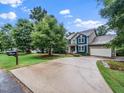Exterior elevation with large driveway, attached garage, and a landscaped yard at 218 Inwood Forest Dr, Raleigh, NC 27603