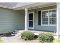 Home's welcoming front porch with green siding, black shutters, and neatly trimmed bushes at 2474 Sumter Dr, Garner, NC 27529
