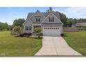 Inviting gray two-story home with a spacious driveway, well-manicured lawn, and mature landscaping at 31 Sweet Birch Ave, Zebulon, NC 27597