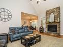 Cozy living room with a stone fireplace, vaulted ceiling, and open access to the dining area at 334 Dell Meadows Pl, Four Oaks, NC 27524