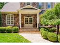 Elegant home entrance with stone steps, pillars, a decorative door, and manicured landscaping at 401 Westbury Dr, Chapel Hill, NC 27516