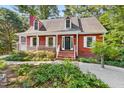 Inviting red home with white trim, a covered porch, and lush landscaping creating curb appeal at 6728 Glen Forrest Dr, Chapel Hill, NC 27517