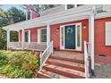 Close-up of the front porch with brick steps, white railings, and a decorative wreath on the front door at 6728 Glen Forrest Dr, Chapel Hill, NC 27517