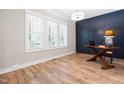 Bright bedroom features wood floors, large windows, neutral walls, a modern blue accent wall and stylish desk at 1004 Snow Peak Ct, Raleigh, NC 27603