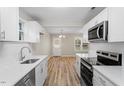 Modern kitchen with white cabinets, stainless steel appliances, white countertops, and wood-look flooring at 1611 Poole Rd, Raleigh, NC 27610