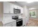 Updated kitchen with white cabinets, stainless steel appliances, white countertops, and modern backsplash at 1611 Poole Rd, Raleigh, NC 27610
