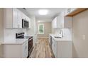 Bright kitchen featuring white cabinets, stainless steel appliances, white countertops, and wood-look flooring at 1611 Poole Rd, Raleigh, NC 27610