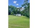 Charming white home with a lush green lawn and a metal carport, surrounded by mature trees at 229 Maple Dr, Oxford, NC 27565