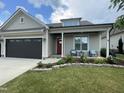 Beautiful home with a red front door, covered porch, and green lawn, showcasing lovely landscaping at 3 Meadowrue Ln, Youngsville, NC 27596