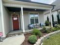Inviting front porch with chairs, stone accents, and verdant landscaping, perfect for relaxing outdoors at 3 Meadowrue Ln, Youngsville, NC 27596