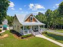 Aerial view of a charming home with a welcoming front porch and lush green lawn surrounded by mature trees at 4050 Culbreth Rd, Stem, NC 27581