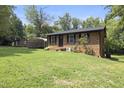 A quaint brick home with black shutters surrounded by a lush, green lawn and a storage shed at 437 Woodsdale Rd, Roxboro, NC 27573