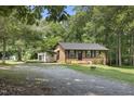 Charming brick home featuring a lush lawn, carport, and an outbuilding, nestled among mature trees at 437 Woodsdale Rd, Roxboro, NC 27573