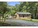 Charming brick home featuring a lush lawn, carport, and an outbuilding, nestled among mature trees at 437 Woodsdale Rd, Roxboro, NC 27573
