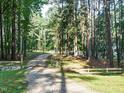 Gated gravel driveway lined by mature trees at the entrance of the property at 45 Softwood Dr, Franklinton, NC 27525