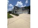 Spacious three-car garage featuring white doors, a wide concrete driveway, and well-maintained landscaping at 820 Christian Light Rd, Fuquay Varina, NC 27526