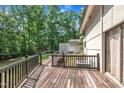 Backyard wooden deck with black railing featuring mature trees and partial view of the house exterior at 8510 Dunlee Falls Rd, Raleigh, NC 27613