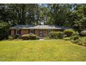 Charming brick home with a well-manicured lawn, mature trees, and lush landscaping at 111 Lattimore Ln, Durham, NC 27713