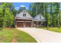 View of the home's exterior with a long driveway, two-car garage, and inviting front porch framed by lush trees at 121 Quarterhorse Dr, Louisburg, NC 27549