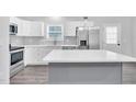 Modern kitchen with white cabinets, stainless steel appliances, and gray island at 1213 Grant St, Durham, NC 27701