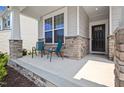 Inviting front porch with stone accents and space for relaxing with chairs at 136 Durie Way, Garner, NC 27529