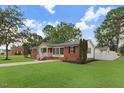 Well-manicured lawn with updated exterior featuring brick and vinyl siding, complemented by mature trees at 201 Shady Lane Dr, Smithfield, NC 27577