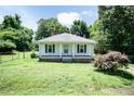 Charming single-story home featuring a covered front porch, white siding, neatly trimmed shutters, and a spacious front yard at 310 Spring St, Durham, NC 27703