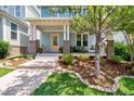 Inviting front porch with seating and a yellow door, enhanced by lush landscaping at 322 Tobacco Farm Way, Chapel Hill, NC 27516