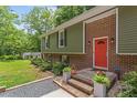 Inviting front entrance with brick accents, lush landscaping, and a bright orange front door at 4404 Oak Park Rd, Raleigh, NC 27612
