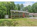 Exterior view of a well-kept home with a green lawn, mature trees and a storage shed at 4404 Oak Park Rd, Raleigh, NC 27612