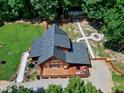 Aerial view of a log cabin showing deck, outbuilding, stone firepit, and lush green lawn at 52 Buoy Dr, Henderson, NC 27537