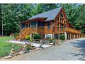 Log home exterior featuring a sprawling deck, tall windows, and mature trees at 52 Buoy Dr, Henderson, NC 27537