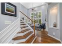 Elegant entryway featuring hardwood floors, a staircase, and a glimpse of the living room's bright windows at 8106 Sommerwell St, Raleigh, NC 27613