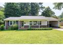 Charming single-story brick home featuring a well-manicured lawn and covered carport on a sunny day at 827 Union St, Cary, NC 27511