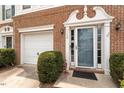 Close up of front door and attached garage of townhome featuring a nicely landscaped walkway at 110 Great Ridge Ct, Morrisville, NC 27560